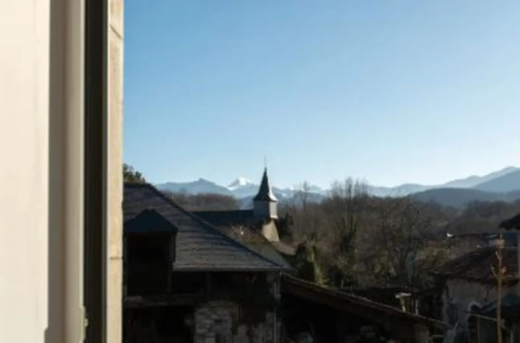 Le clocher du village et les Pyrénées enneigées
